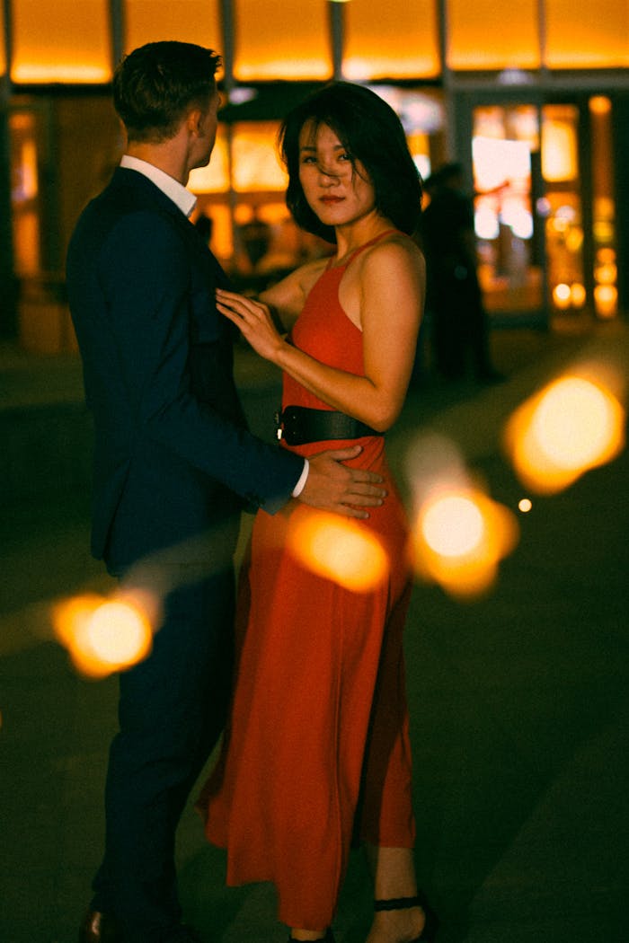 A stylish couple captured in a romantic evening setting with glowing lights.